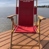 A red deck chair on a deck overlooking the water, equipped with a Yeti Cooler with Blender and ICE.